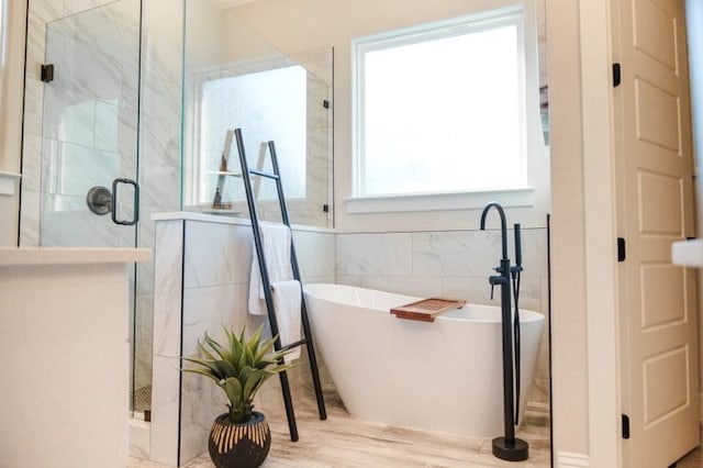 bathroom with tile walls and separate shower and tub