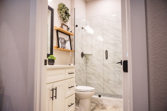 bathroom featuring vanity, a shower with shower door, and toilet