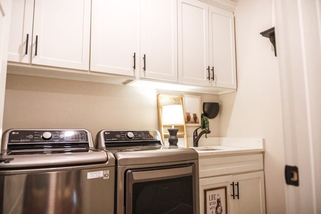 clothes washing area featuring sink, cabinets, and washer and clothes dryer