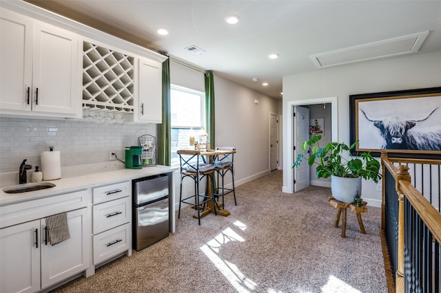 kitchen featuring decorative backsplash, light carpet, sink, white cabinets, and stainless steel fridge