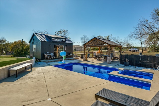 view of swimming pool with an in ground hot tub, a gazebo, an outbuilding, and a patio