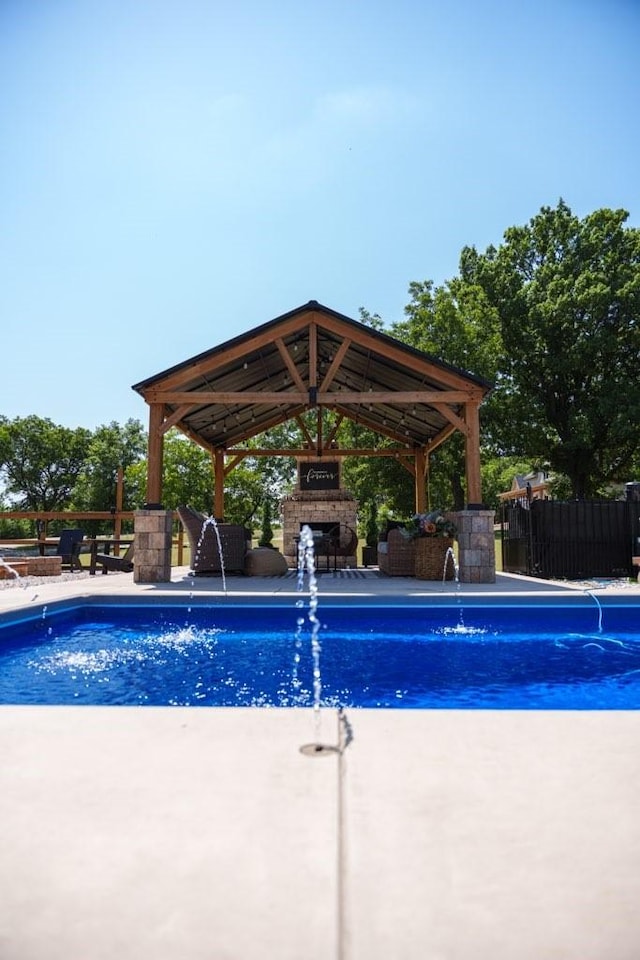 view of swimming pool with an outdoor fireplace, a patio, a gazebo, and pool water feature