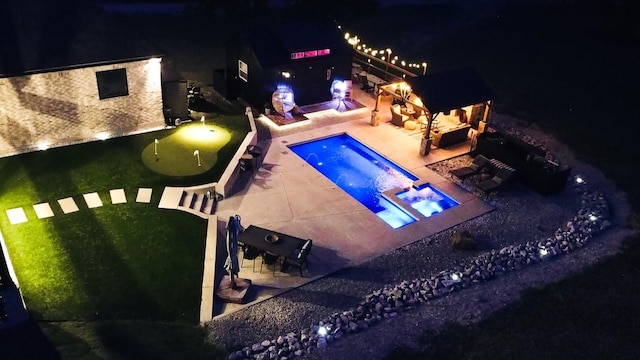 pool at night featuring an in ground hot tub and a patio