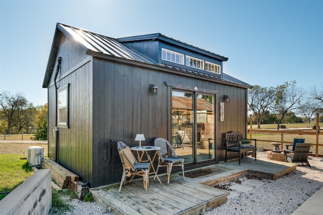 rear view of house with an outbuilding, a wooden deck, and a fire pit