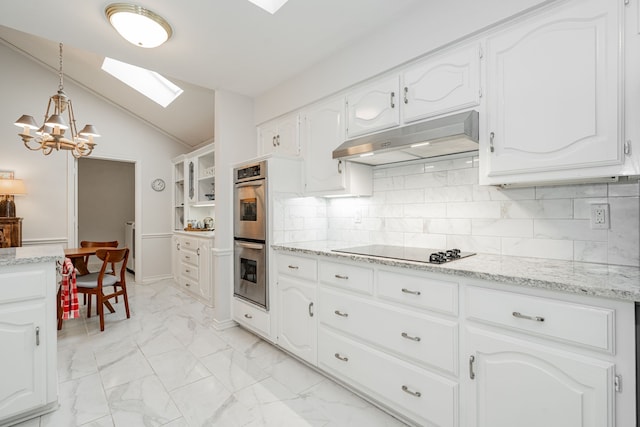 kitchen featuring marble finish floor, vaulted ceiling with skylight, white cabinets, and under cabinet range hood