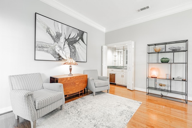 sitting room featuring wood-type flooring and crown molding