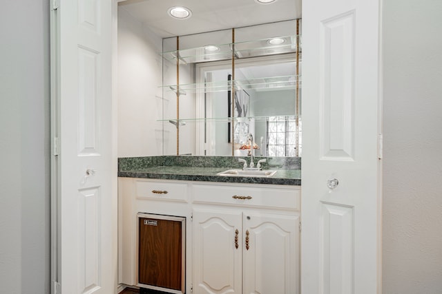 bar with white cabinetry and sink