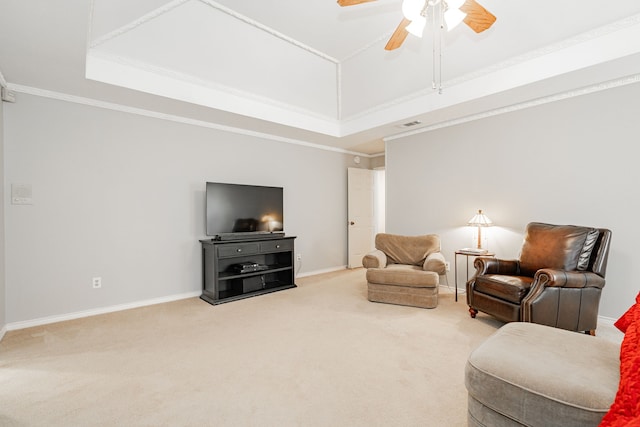 carpeted living room with a raised ceiling, ceiling fan, and crown molding