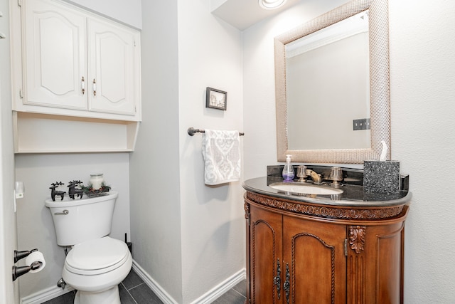 half bath featuring toilet, tile patterned flooring, vanity, and baseboards