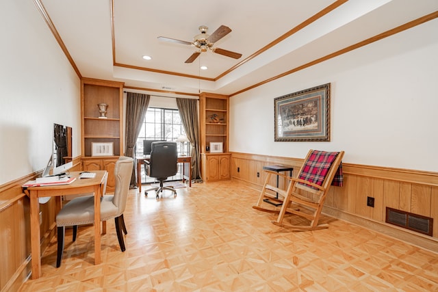 office featuring a tray ceiling, ceiling fan, light parquet flooring, and ornamental molding