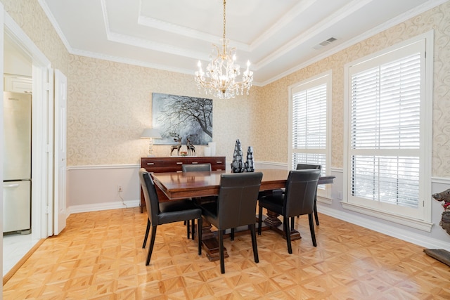 dining space with a notable chandelier, crown molding, a tray ceiling, and light parquet floors