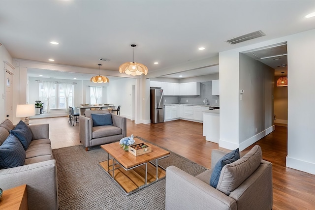 living area featuring recessed lighting, visible vents, and wood finished floors