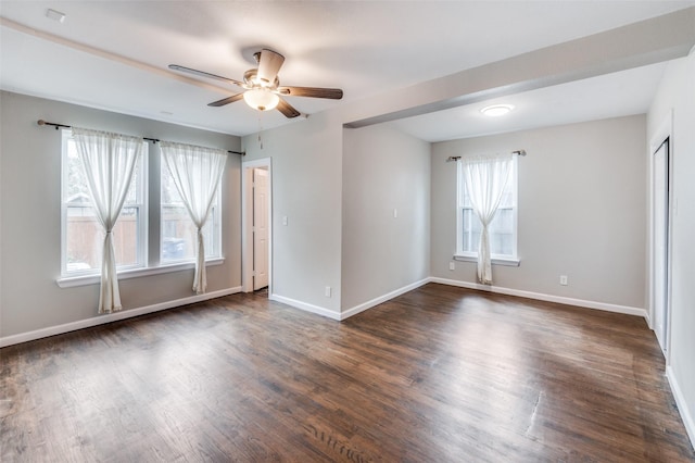 empty room featuring dark wood-style flooring, a ceiling fan, and baseboards