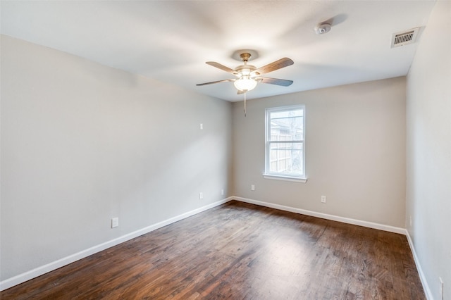 spare room featuring ceiling fan, baseboards, visible vents, and dark wood finished floors