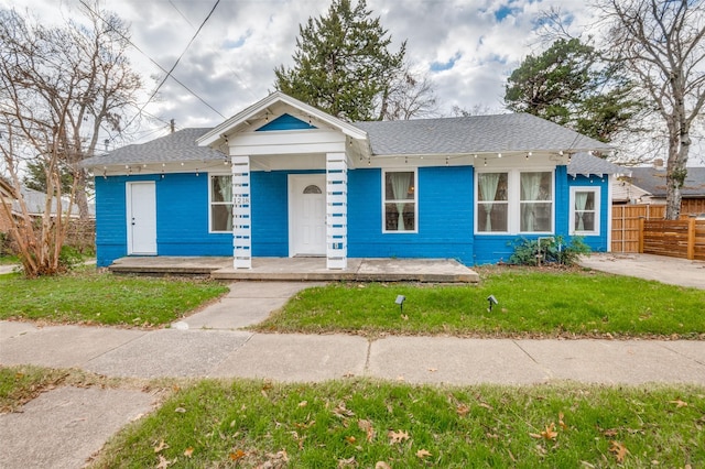 bungalow-style house with a front yard, covered porch, and fence