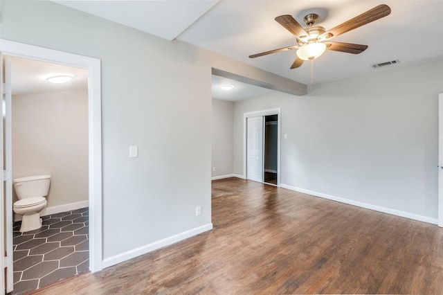 spare room with baseboards, visible vents, ceiling fan, and dark wood-style flooring