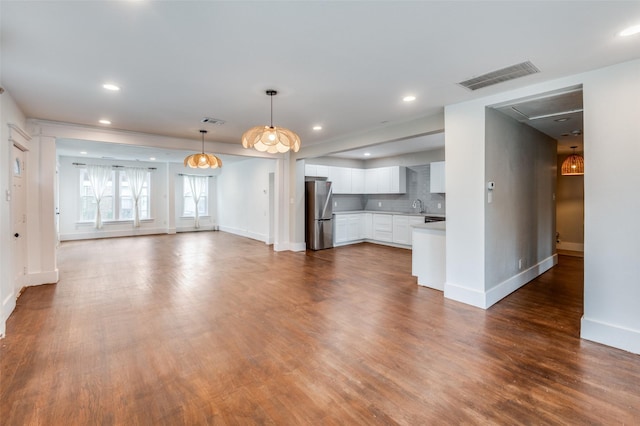 unfurnished living room with visible vents, dark wood finished floors, and a sink