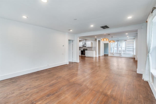 unfurnished living room with baseboards, visible vents, dark wood finished floors, an inviting chandelier, and recessed lighting