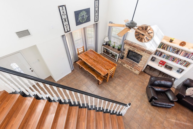 living room featuring hardwood / wood-style flooring, ceiling fan, a towering ceiling, and a fireplace