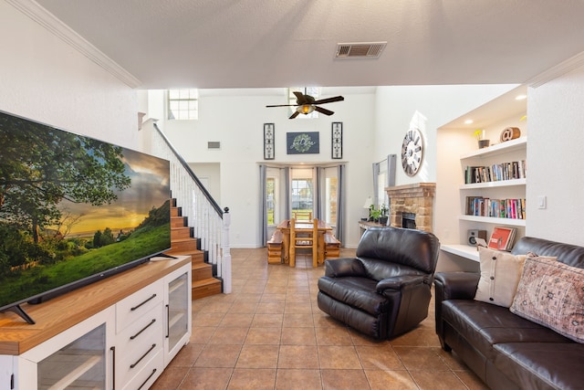 living room featuring built in shelves, crown molding, light tile patterned flooring, and ceiling fan