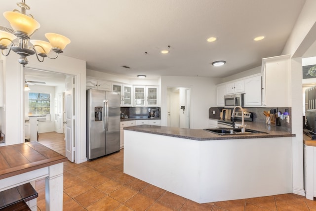 kitchen featuring kitchen peninsula, decorative backsplash, appliances with stainless steel finishes, decorative light fixtures, and white cabinetry