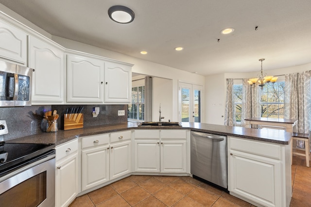 kitchen featuring backsplash, stainless steel appliances, sink, a chandelier, and white cabinetry