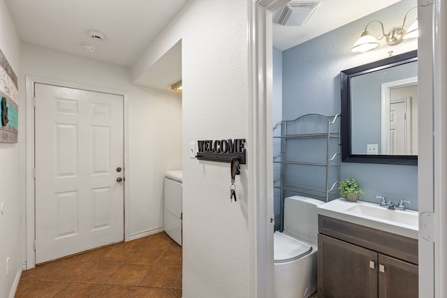 bathroom featuring washer / dryer, vanity, and tile patterned floors