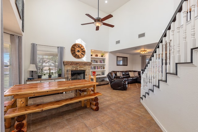 living room featuring built in shelves, ceiling fan, a towering ceiling, and light tile patterned floors