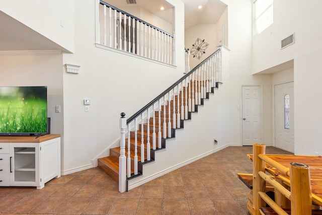 stairs with tile patterned floors, a high ceiling, and ornamental molding