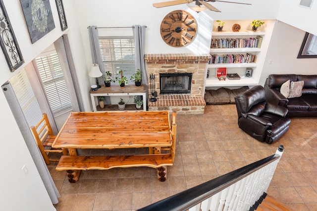 living room featuring tile patterned floors, built in shelves, ceiling fan, and a fireplace