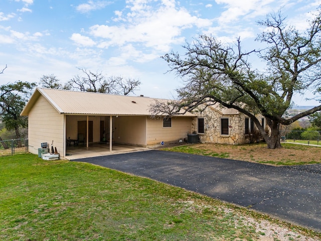 view of front of property featuring a front lawn, central AC unit, and a carport