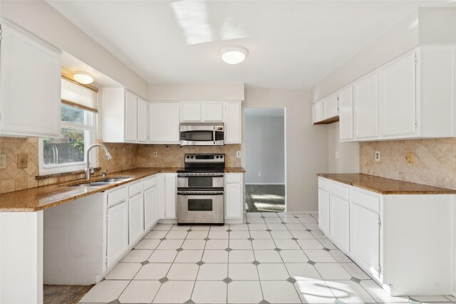 kitchen featuring light stone countertops, white cabinetry, sink, stainless steel appliances, and decorative backsplash