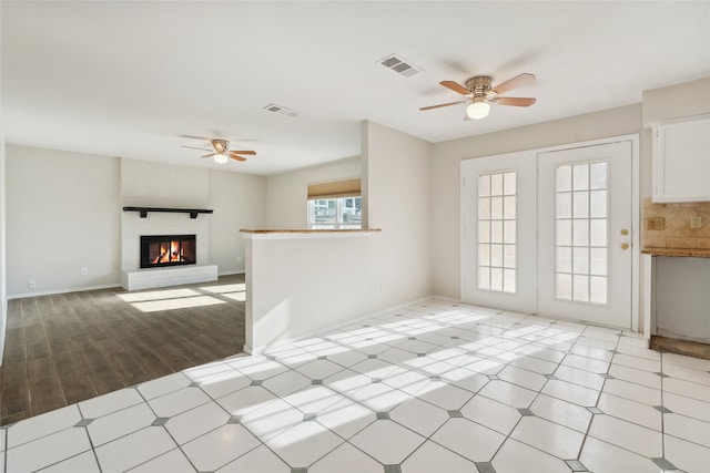 unfurnished living room featuring ceiling fan, a fireplace, and light hardwood / wood-style floors