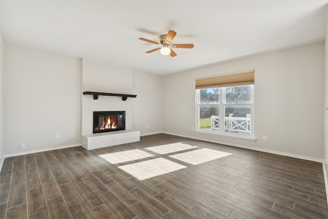 unfurnished living room with ceiling fan, dark wood-type flooring, and a brick fireplace