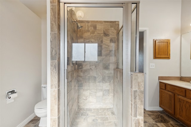 bathroom featuring vanity, a shower with shower door, and toilet