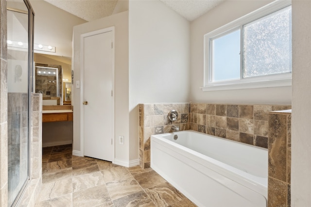 bathroom featuring a textured ceiling, tile walls, and independent shower and bath