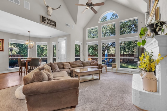 carpeted living room featuring a brick fireplace, high vaulted ceiling, and ceiling fan