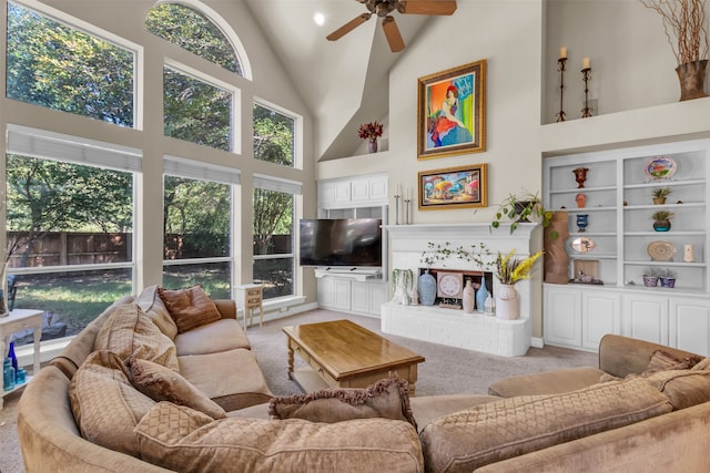 living room with ceiling fan, light colored carpet, high vaulted ceiling, and a brick fireplace