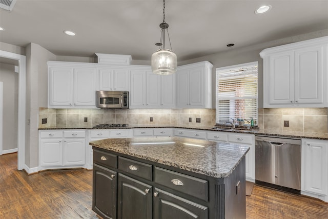 kitchen featuring sink, dark hardwood / wood-style floors, pendant lighting, white cabinets, and appliances with stainless steel finishes