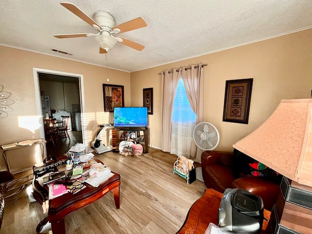 living room with ceiling fan, hardwood / wood-style floors, a textured ceiling, and ornamental molding