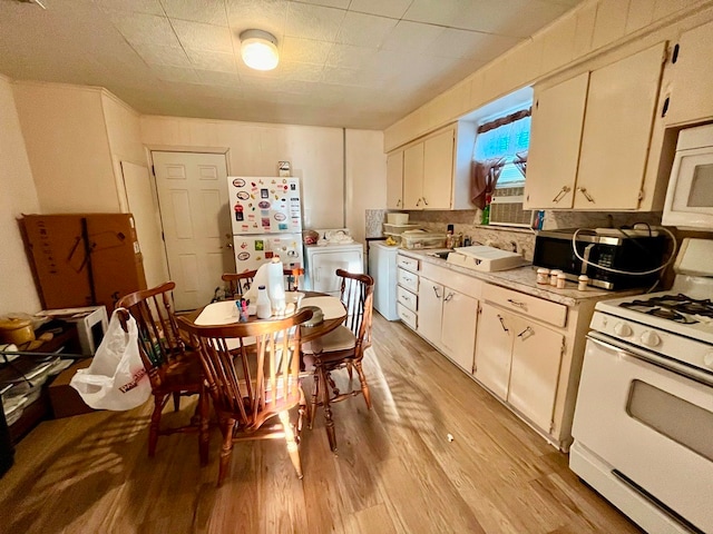 kitchen featuring light wood-type flooring, white appliances, and white cabinetry