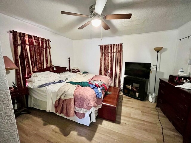 bedroom featuring ceiling fan, wood-type flooring, and a textured ceiling