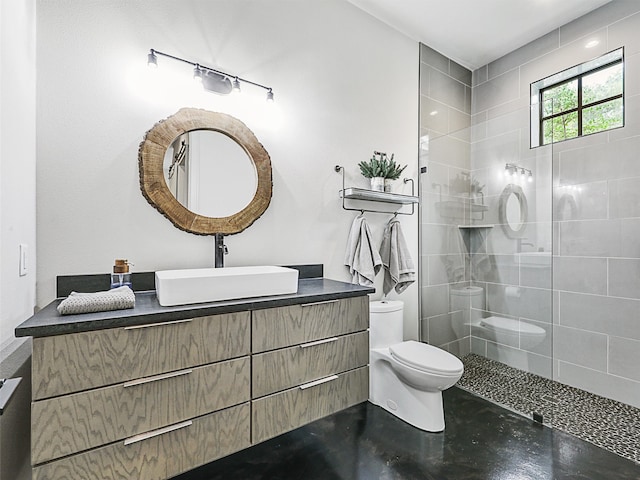 bathroom with concrete flooring, vanity, tiled shower, and toilet