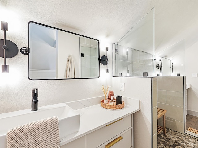 bathroom featuring vanity, a shower, and a textured ceiling