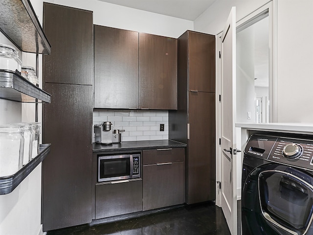 kitchen featuring backsplash, stainless steel microwave, dark brown cabinets, and washer / dryer