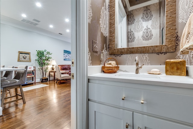 bathroom with hardwood / wood-style flooring, vanity, and ornamental molding