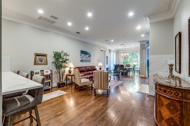 living room with dark wood-type flooring, a notable chandelier, and ornamental molding