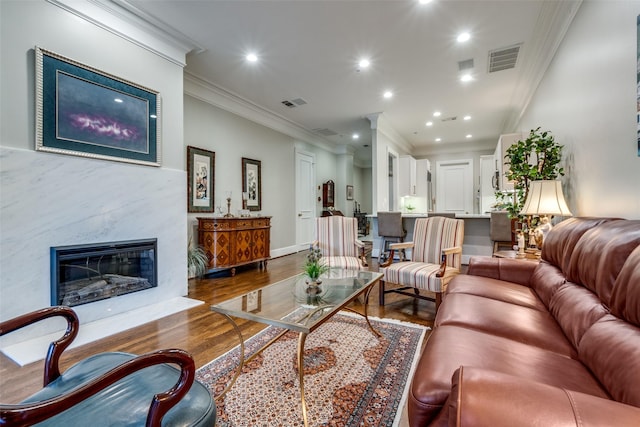 living room with a high end fireplace, dark wood-type flooring, and ornamental molding