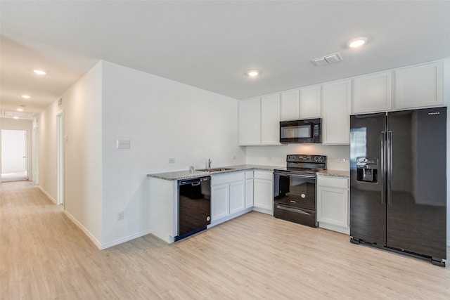 kitchen featuring sink, light stone counters, light hardwood / wood-style flooring, white cabinets, and black appliances