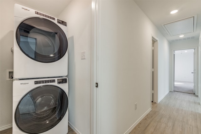 laundry room with light hardwood / wood-style floors and stacked washer / drying machine